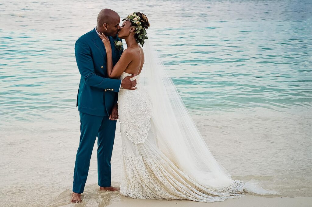 Newly wedded couple embracing on beach.